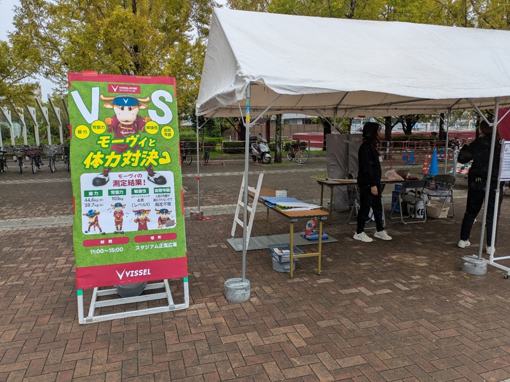 スタジアム正面広場に出展された「モーヴィと体力対決」体力測定ブースの看板とテント